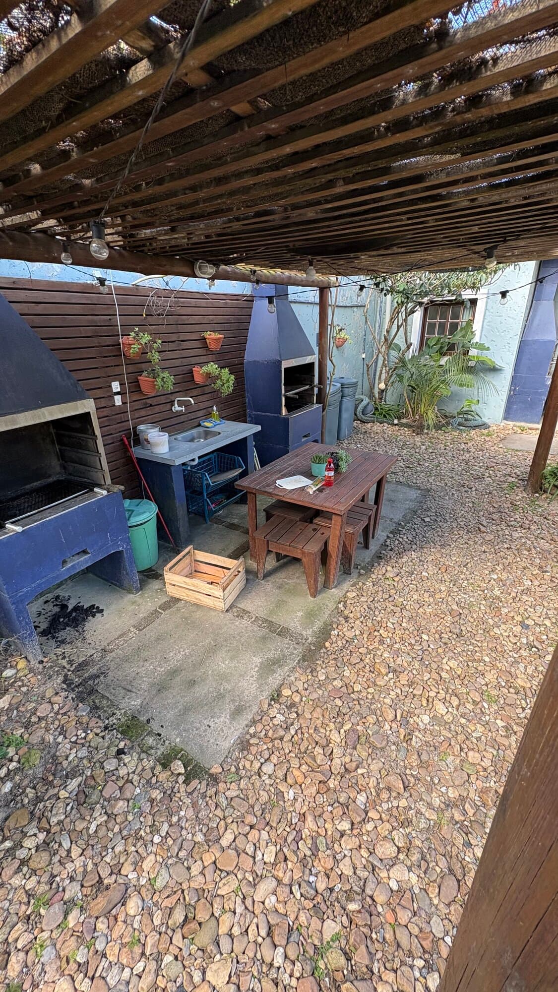 Área de churrasqueira coberta, com mesa e bancos