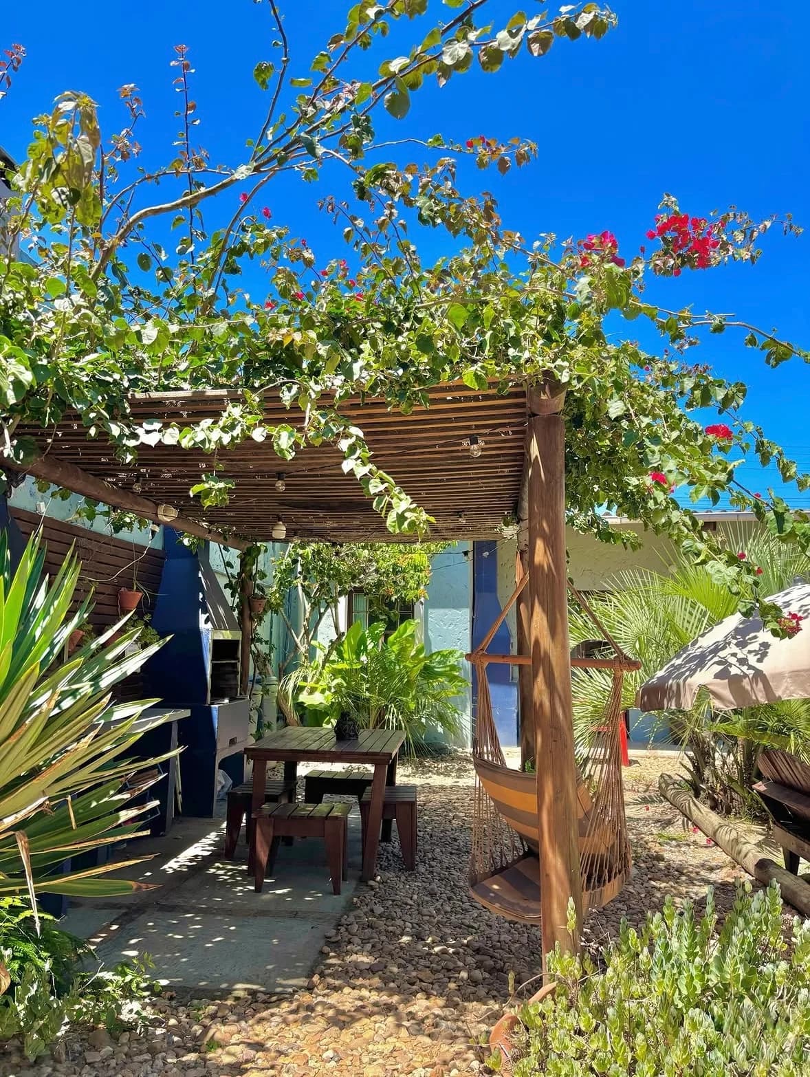 Pergolado florido com mesa e rede no jardim